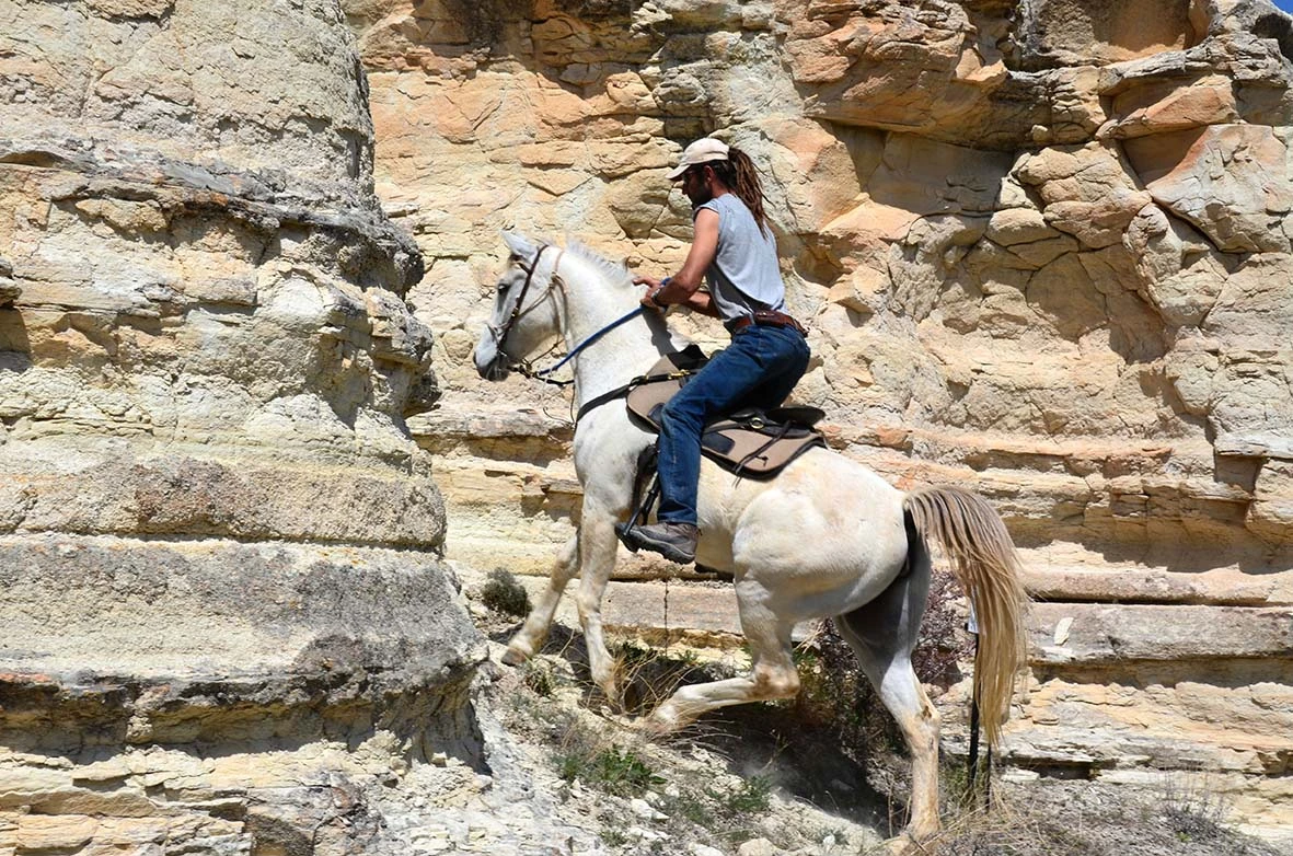 Guide sur son cheval encagé dans une chemin étroit et caillouteux de la randonnée à cheval en Cappadoce, en Turquie