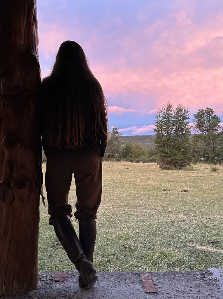 une femme de dos qui contemple le ciel rose