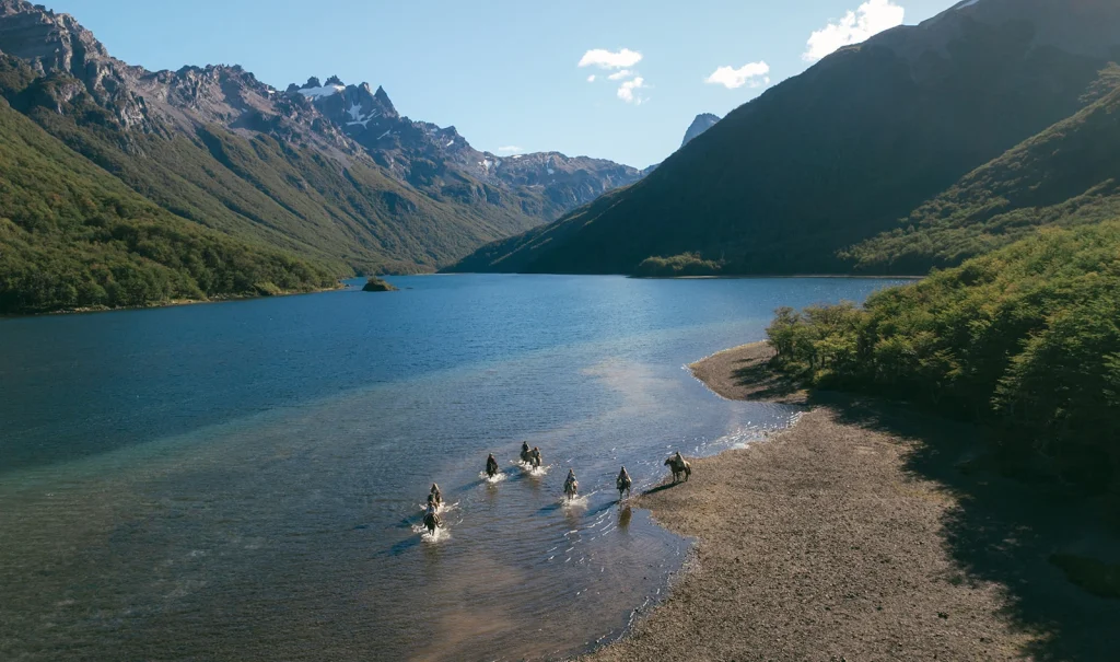 des cavaliers à cheval qui marchent dans l'eau d'un lac vue du haut