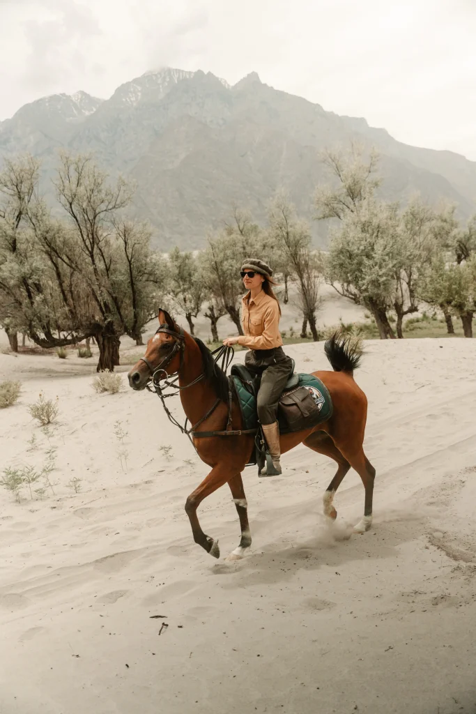 une cavalière au trot sur un cheval arabe dans le desert du pakistan
