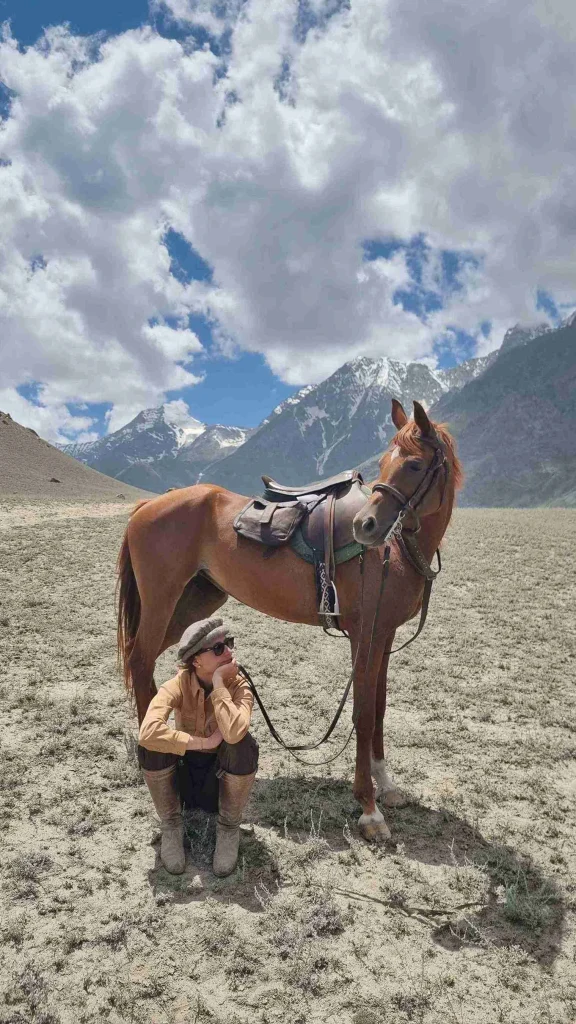 une cavalière assise et son cheval qui regarde dans l'autre direction dans les montagnes de karakoram au pakistan