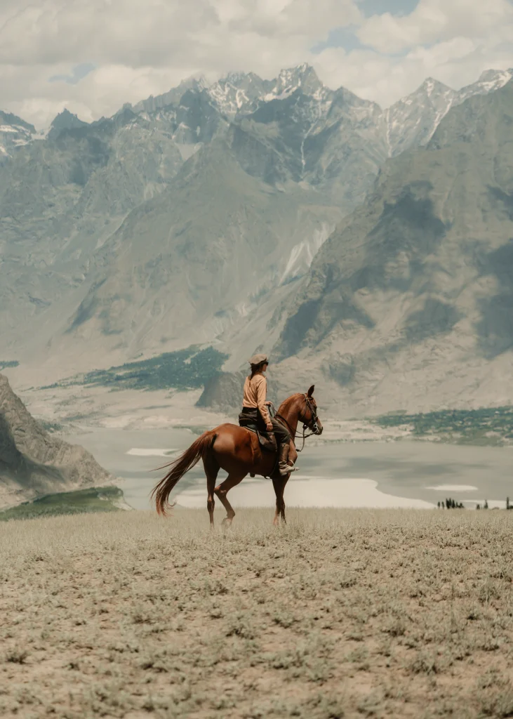 une cavalière sur un cheval arabe au sommet d'une montagne lors d'un voyage à cheval au Pakistan dans les montagnes du Karakoram